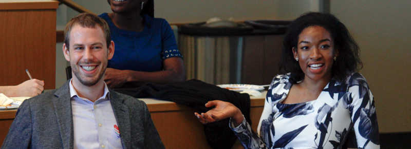 A small group of people sitting in a professional setting, smiling and engaged in discussion.