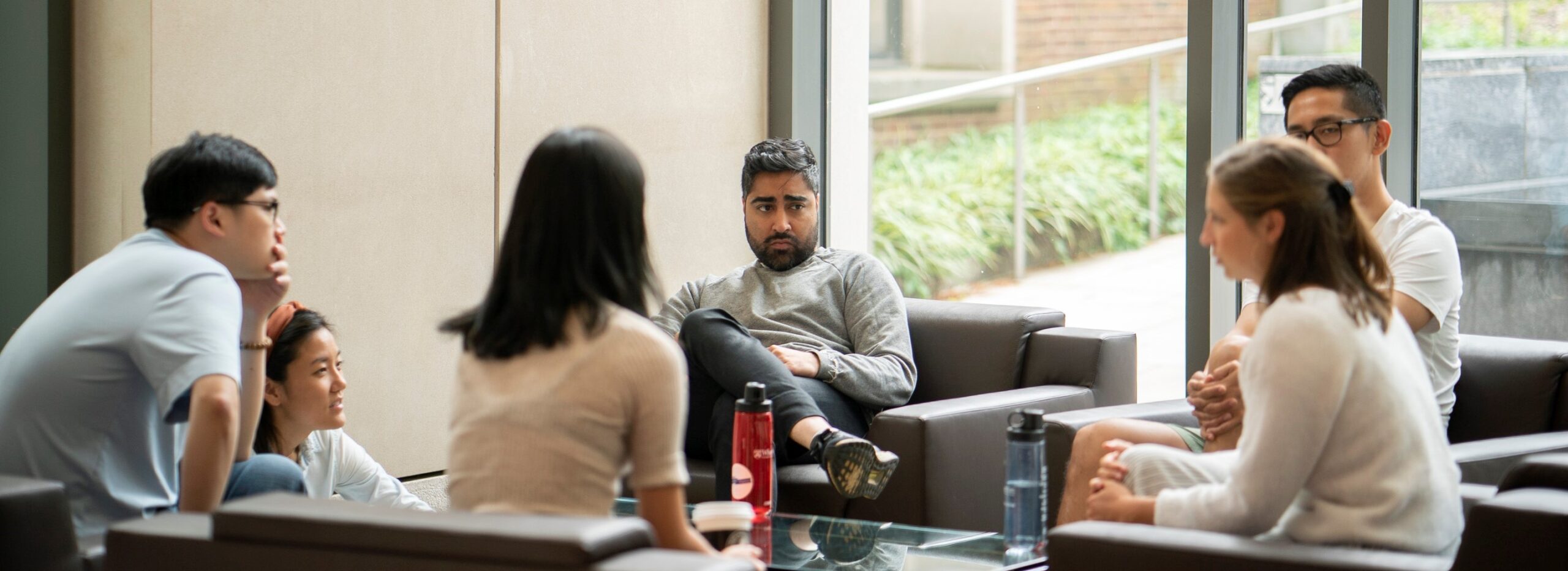 A group of people sitting in a casual indoor setting, engaged in conversation.