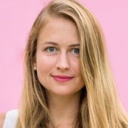 Headshot of a person with long blonde hair against a pink background.